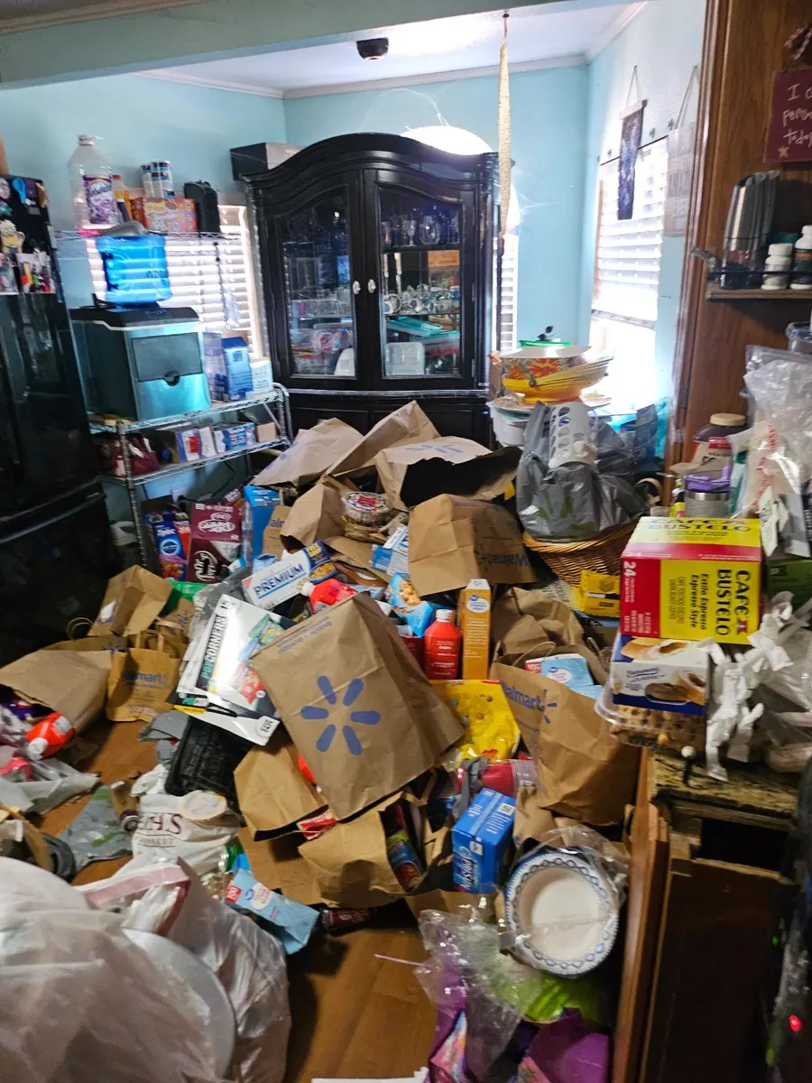 Dining room filled with grocery bags, boxes and household items before a hoarding cleanup in a Sacramento-area home
