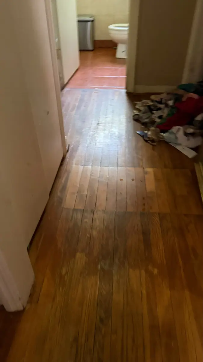 Hallway with debris piled against the wall before a hoarding cleanup in a Sacramento home
