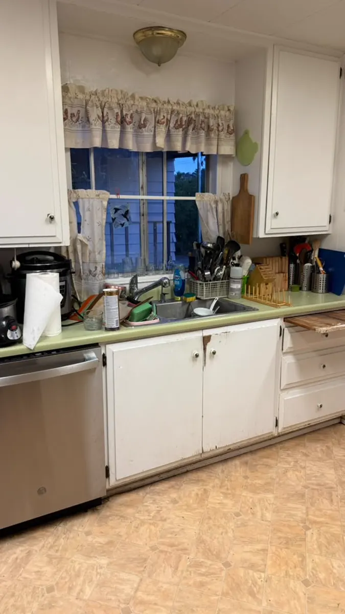 Cluttered kitchen counter and sink full of dishes and utensils before cleanup
