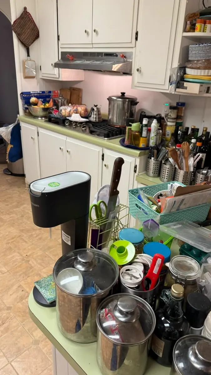 Kitchen counters stacked with pots, jars and appliances before a hoarding cleanup