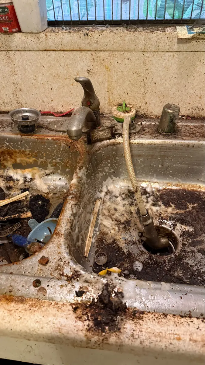Kitchen sink covered in grease and buildup before hoarding cleanup