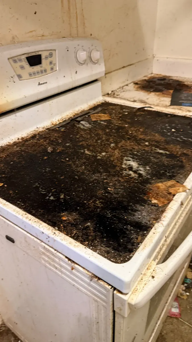 Glass stovetop caked with burnt residue before cleanup